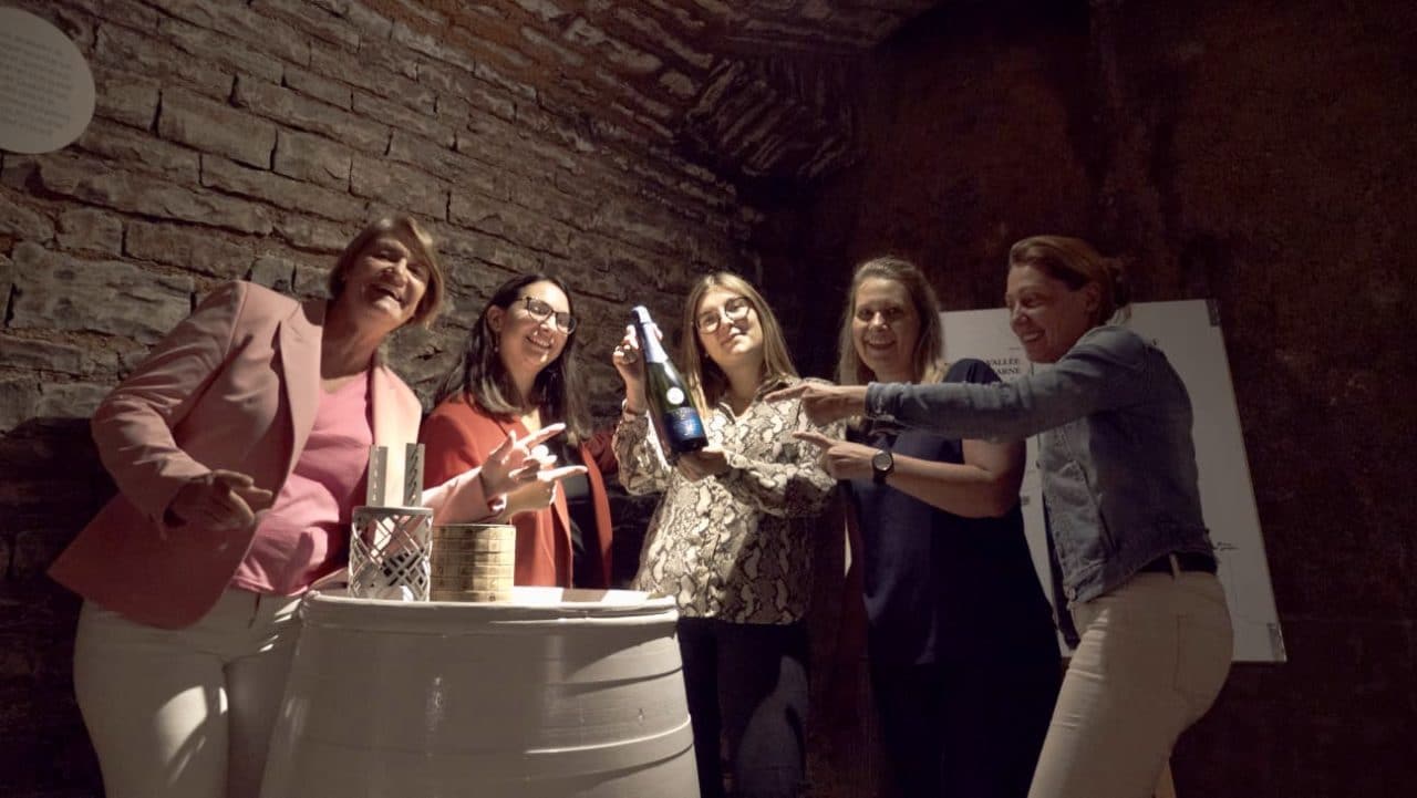 l'office de tourisme de la côte des Bar pose après avoir libéré la bouteille de champagne