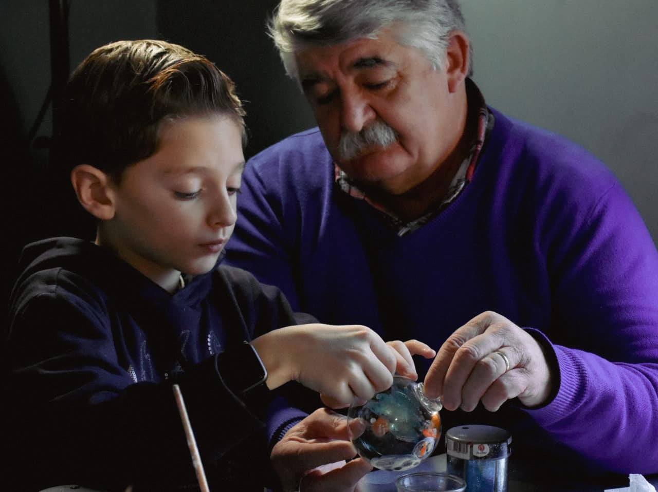 Un grand père et son petit fils décorent une boule de Noël