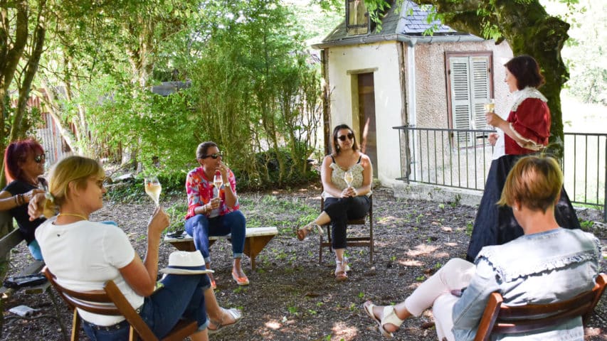 Des personnes écoutent la guide Sarah hacquart au bord de la seine accompagnée d'une flûte de champagne
