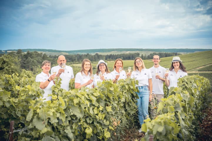 équipe de l'office de tourisme dans les vignes avec coupe de champagne et polo le coq sportif